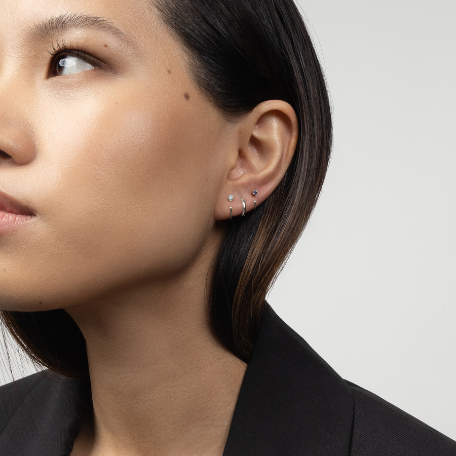 Lifestyle profile shot of a woman wearing the Stay Close Aquamarine Hoop in silver.