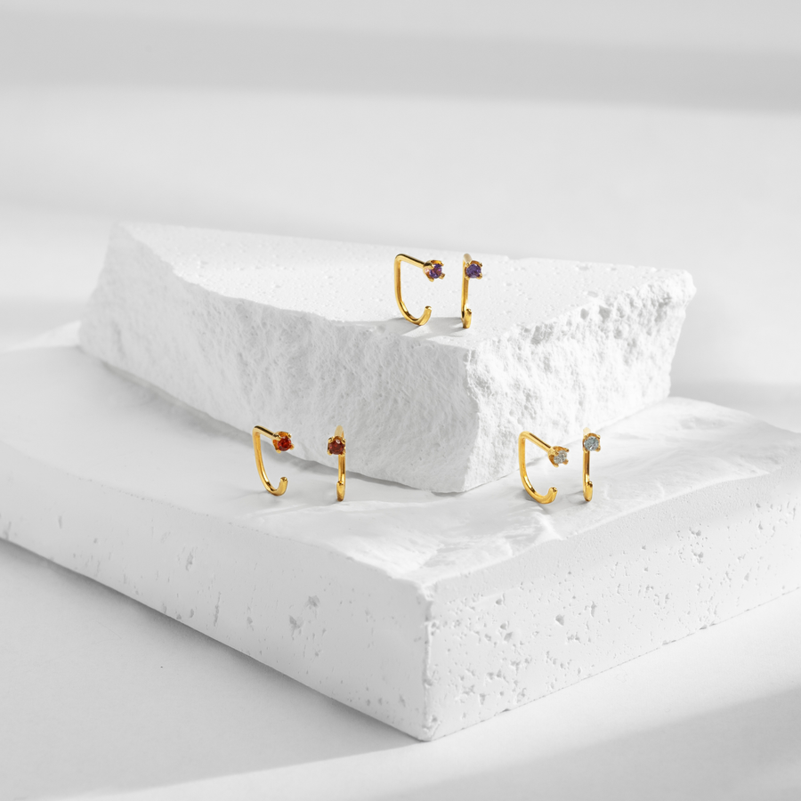 Gold Stay Close Hoops on a textured white surface