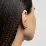 Close-up of a person wearing Stay Close Hoops from the back with a neutral background