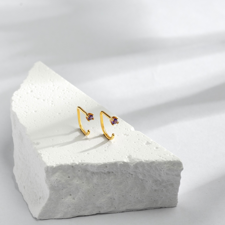 Gold Stay Close Amethyst Hoop with purple gemstones on a white stone block
