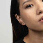 Close-up of a person wearing gold Stay Close Aquamarine Hoop with a neutral background