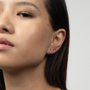 Close-up of a woman's ear with Stay Close Garnet Hoop against a neutral background
