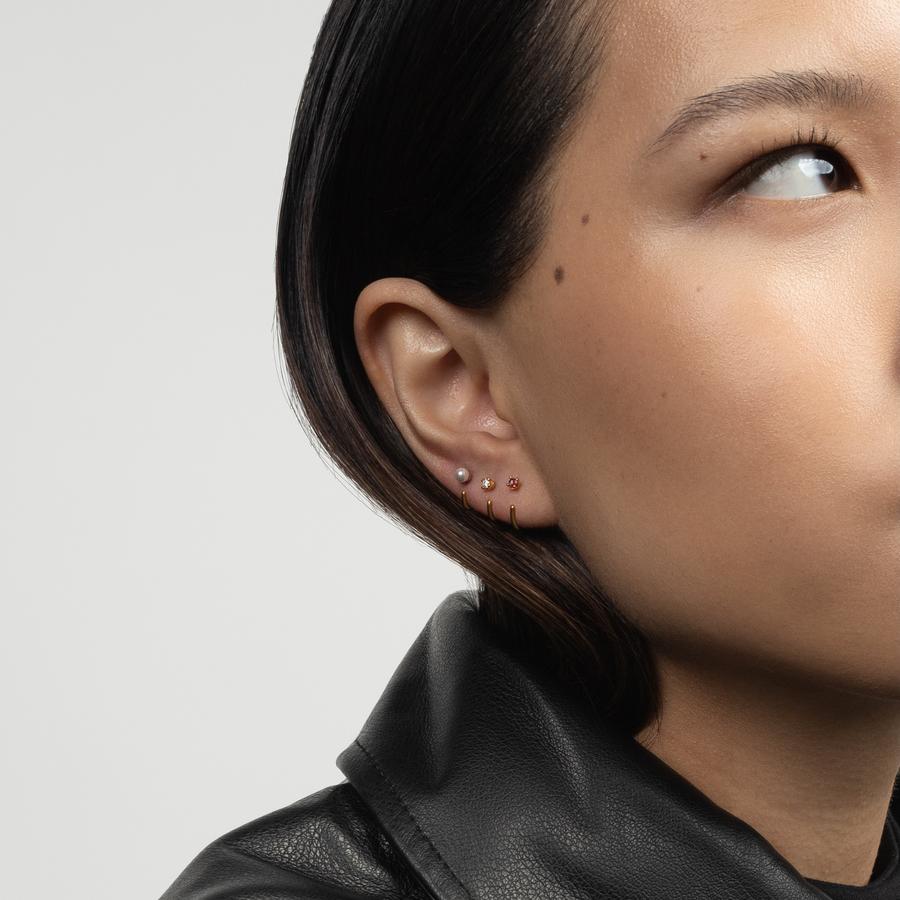 Close-up of a person wearing Stay Close Garnet Hoop and Pearl Hoop with a neutral background