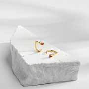 Gold Stay Close Garnet Hoop on a textured white block with a light gray background