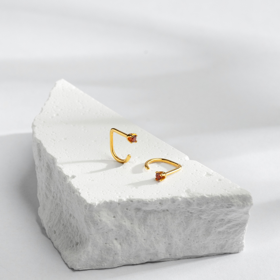 Gold Stay Close Garnet Hoop on a textured white block with a light gray background