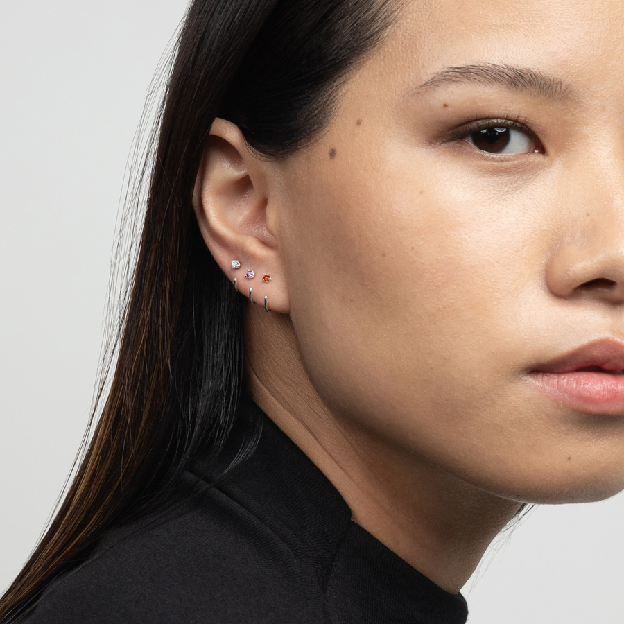 Close-up of a woman wearing a silver Stay Close Amethyst Hoop against a neutral background